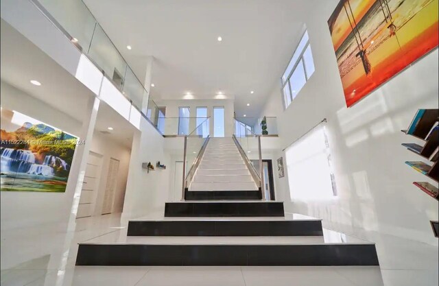 staircase featuring a towering ceiling and recessed lighting