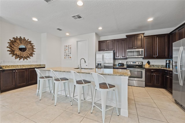 kitchen featuring sink, a kitchen bar, an island with sink, and appliances with stainless steel finishes