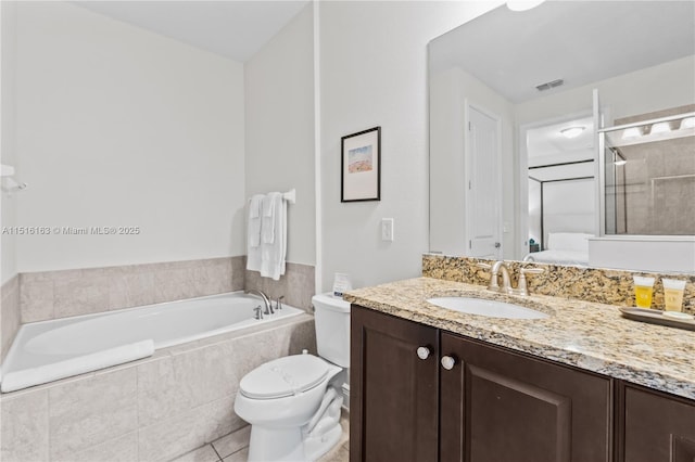 bathroom with vanity, toilet, tile patterned flooring, and tiled bath