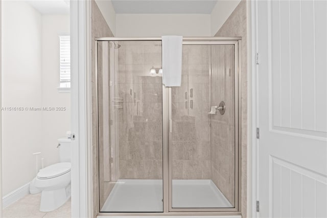 bathroom featuring a shower with door, tile patterned floors, and toilet