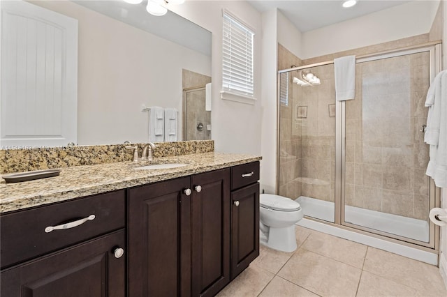 bathroom with tile patterned flooring, vanity, a shower with shower door, and toilet