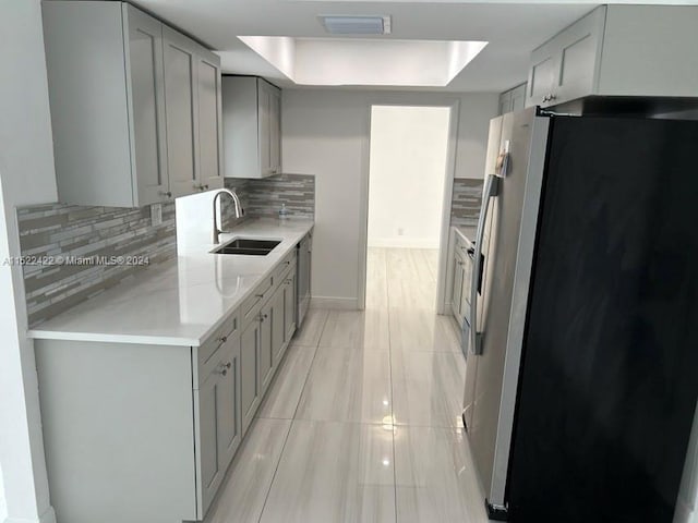 kitchen with tasteful backsplash, appliances with stainless steel finishes, gray cabinets, and sink