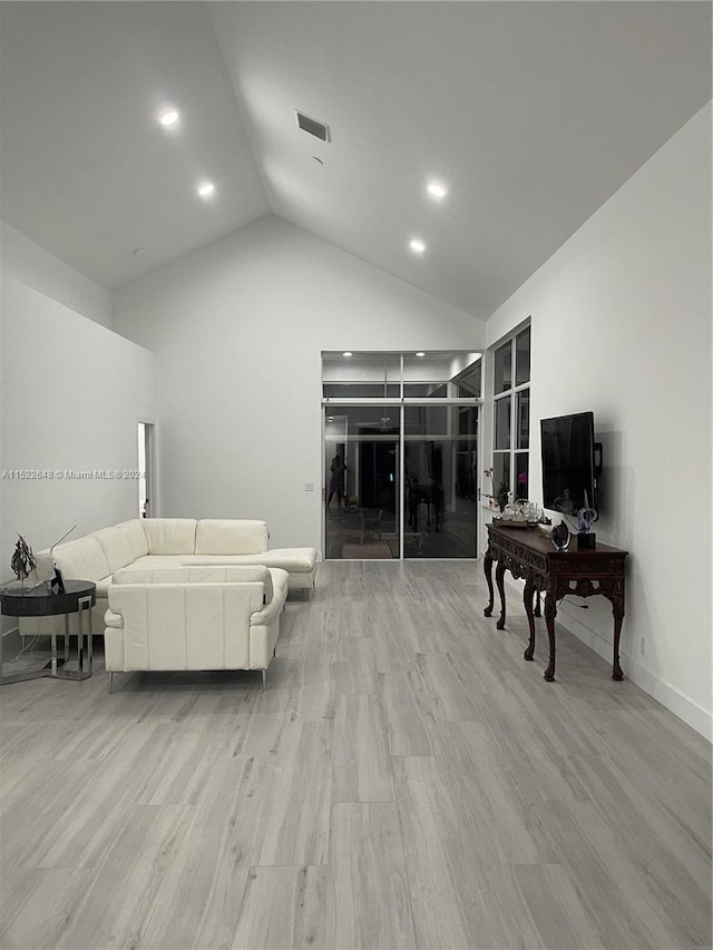 living room with high vaulted ceiling and light wood-type flooring