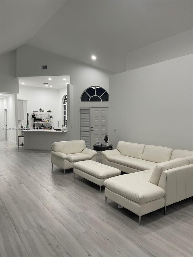 living room featuring light hardwood / wood-style floors and high vaulted ceiling