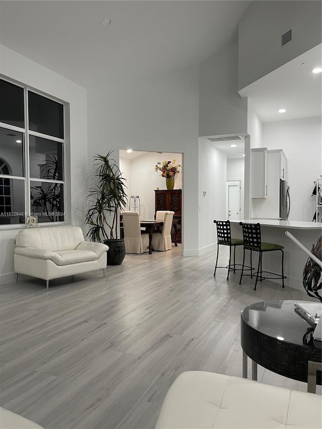 living room featuring light hardwood / wood-style floors and a towering ceiling