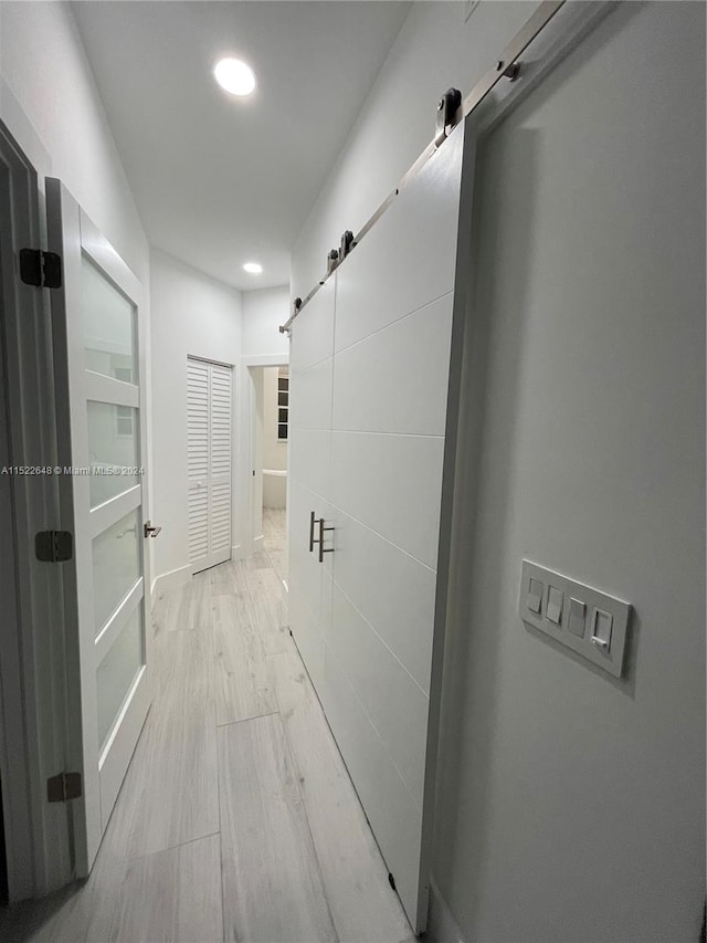 hall featuring a barn door and light hardwood / wood-style floors