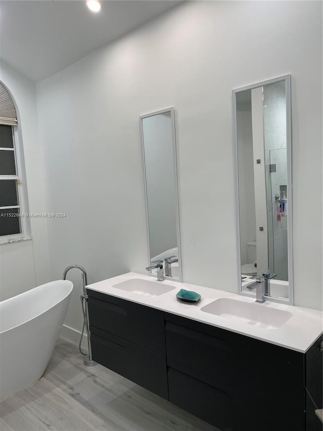 bathroom with a washtub, dual sinks, and large vanity