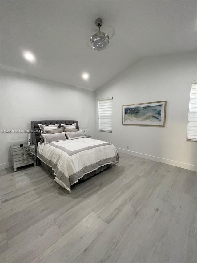 bedroom featuring multiple windows, vaulted ceiling, and light hardwood / wood-style flooring