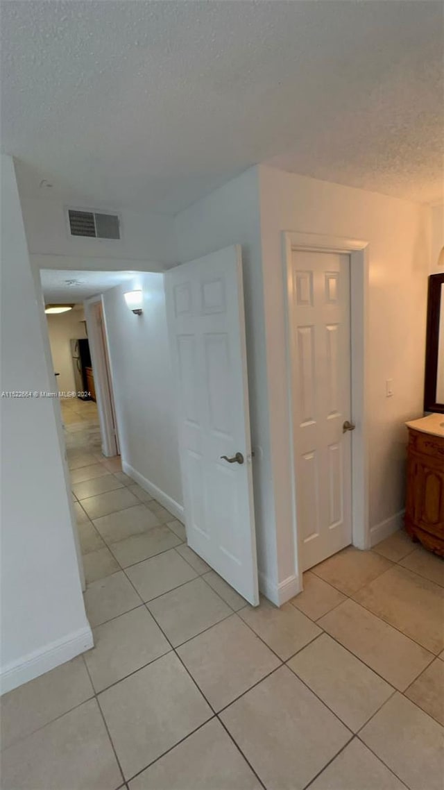 corridor featuring light tile flooring and a textured ceiling