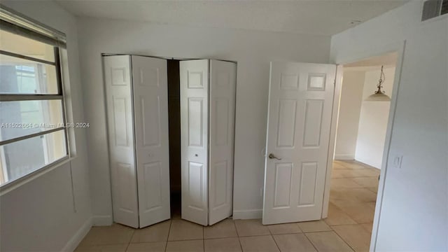 unfurnished bedroom featuring multiple windows, light tile flooring, and two closets