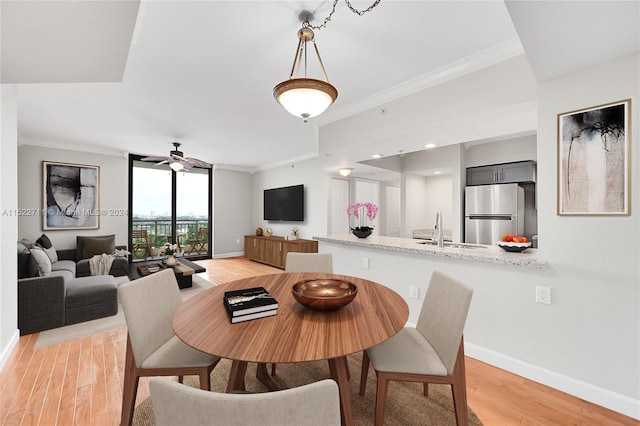 dining space featuring light wood-type flooring, ceiling fan, ornamental molding, and sink