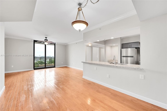 unfurnished living room featuring ceiling fan, sink, wood-type flooring, and ornamental molding