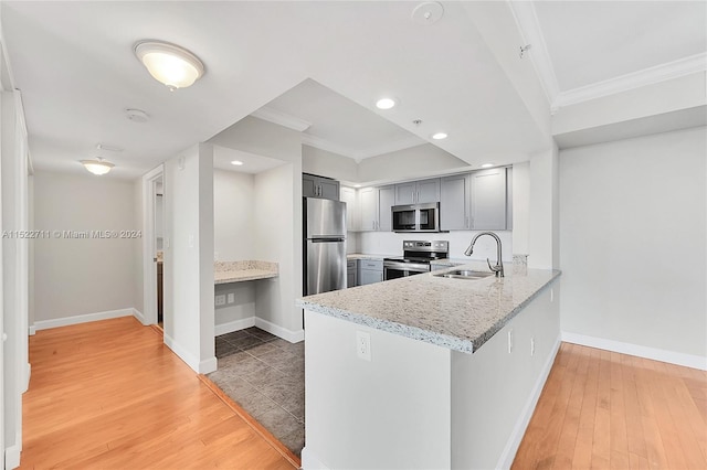 kitchen with gray cabinetry, sink, stainless steel appliances, light stone counters, and hardwood / wood-style flooring