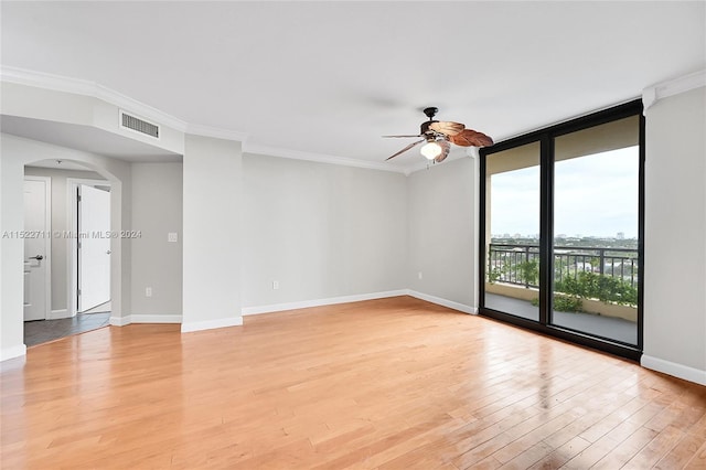 empty room featuring ceiling fan, light hardwood / wood-style floors, ornamental molding, and expansive windows