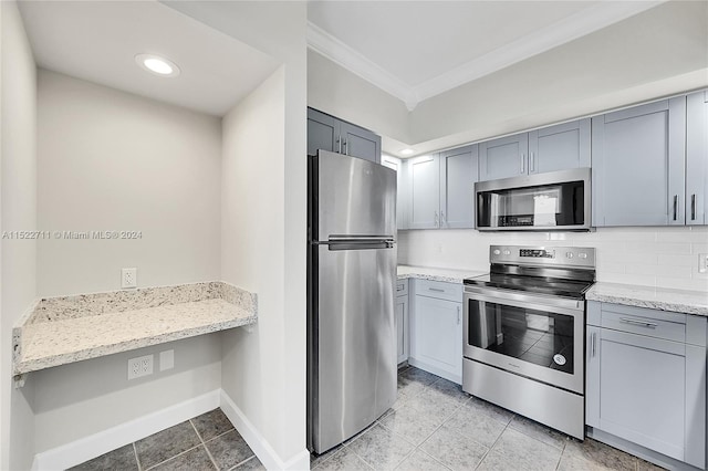 kitchen featuring gray cabinetry, crown molding, decorative backsplash, light stone counters, and stainless steel appliances