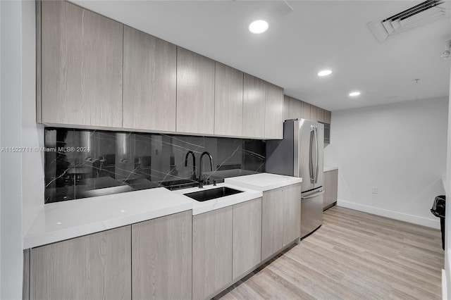 kitchen featuring sink, light brown cabinets, backsplash, stainless steel fridge, and light wood-type flooring