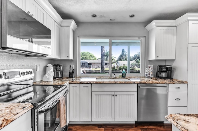 kitchen featuring light stone countertops, dark hardwood / wood-style floors, appliances with stainless steel finishes, sink, and white cabinets