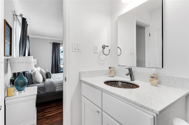 bathroom featuring vanity with extensive cabinet space, hardwood / wood-style flooring, and ornamental molding