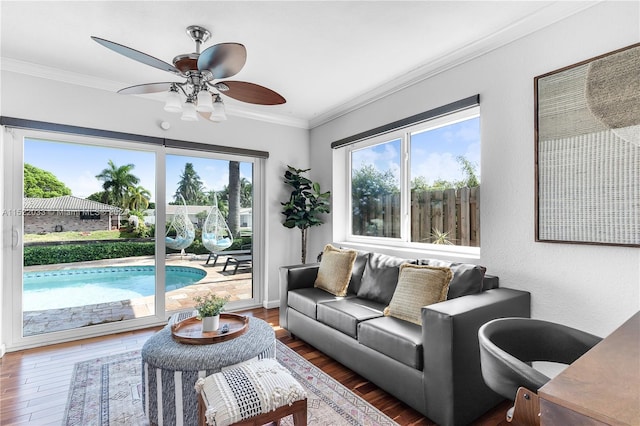 living room featuring dark wood-type flooring, ceiling fan, a wealth of natural light, and ornamental molding