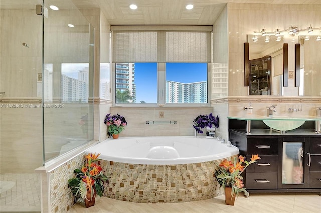 bathroom with tile walls, tile floors, a relaxing tiled bath, and large vanity