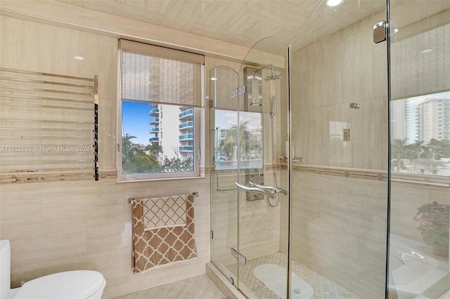 bathroom with toilet, tile flooring, an enclosed shower, and tile walls