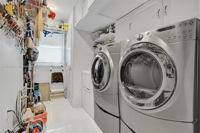 laundry room with washing machine and dryer, light tile floors, and cabinets