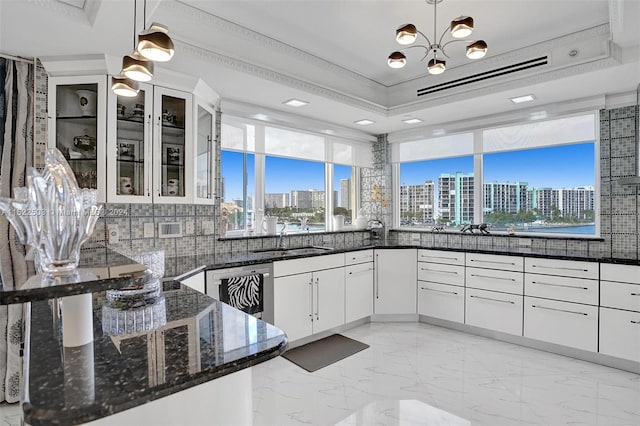 kitchen with dark stone counters, backsplash, decorative light fixtures, and white cabinetry