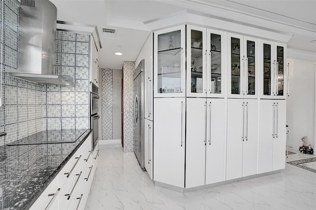 kitchen featuring light tile floors, white cabinets, dark stone countertops, and wall chimney range hood