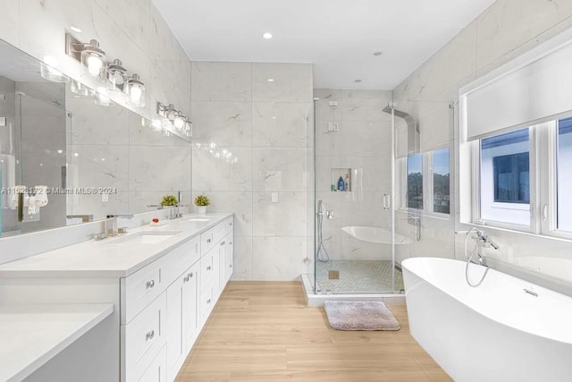 bathroom with tile walls, independent shower and bath, and dual vanity