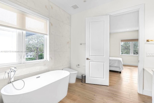 bathroom featuring plenty of natural light, hardwood / wood-style flooring, and tile walls