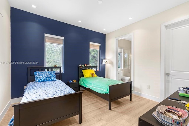 bedroom featuring connected bathroom and light hardwood / wood-style floors