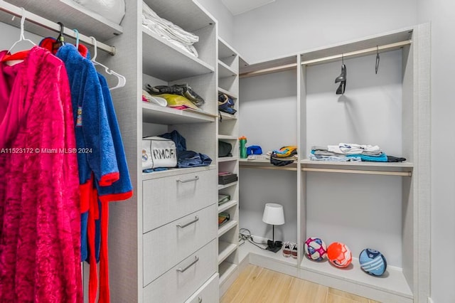 walk in closet with light hardwood / wood-style flooring