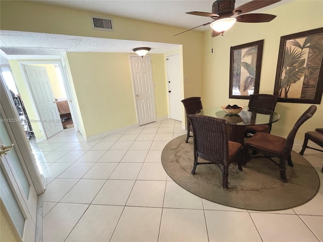 dining room with a textured ceiling, ceiling fan, and light tile floors