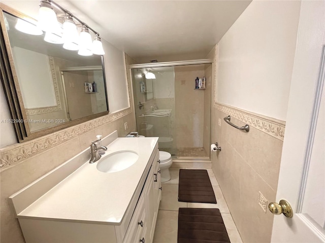 bathroom with toilet, large vanity, tile walls, tile floors, and an enclosed shower