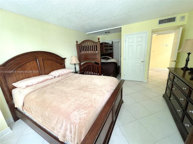 tiled bedroom with a closet and a textured ceiling