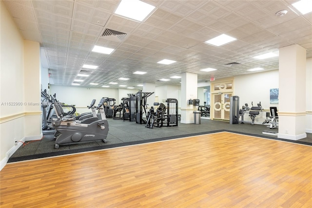 exercise room with hardwood / wood-style floors and a drop ceiling