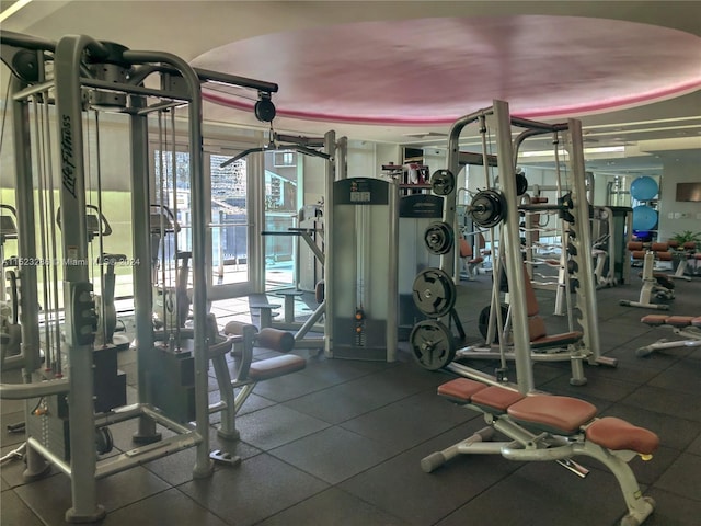 exercise room with dark tile floors and a tray ceiling