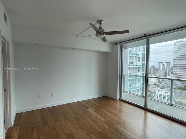 spare room with floor to ceiling windows, ceiling fan, and dark hardwood / wood-style floors