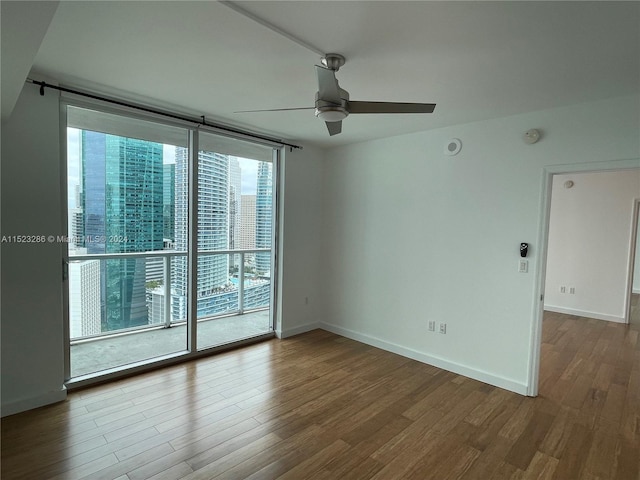 empty room with ceiling fan, dark hardwood / wood-style floors, and a wealth of natural light