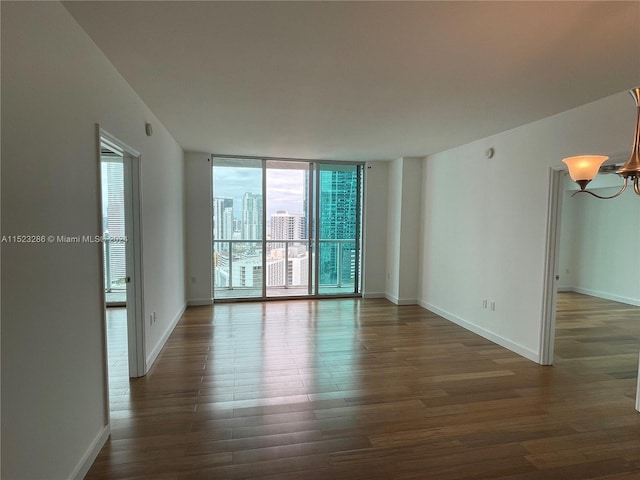 spare room with an inviting chandelier and dark wood-type flooring