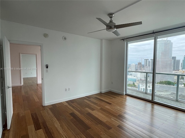 spare room with dark hardwood / wood-style floors, ceiling fan, and a wall of windows