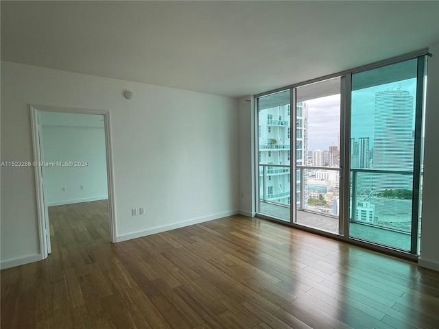 unfurnished room with floor to ceiling windows and dark hardwood / wood-style floors