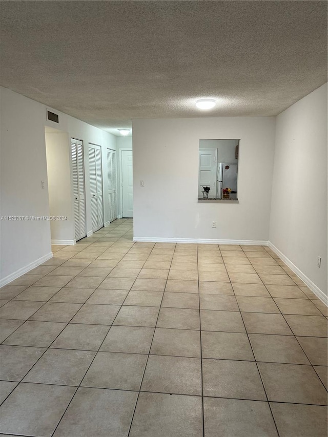 tiled spare room with a textured ceiling