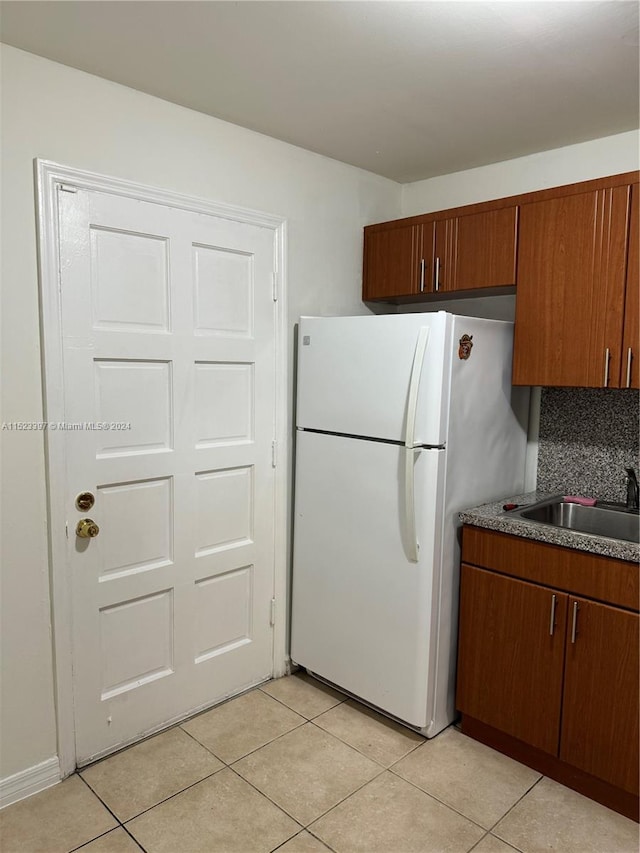 kitchen with backsplash, sink, white fridge, and light tile floors