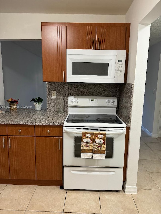 kitchen featuring backsplash, white appliances, and light tile floors