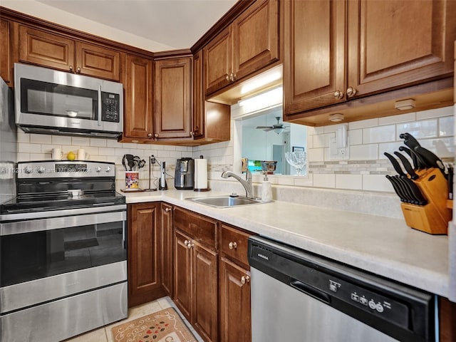 kitchen with appliances with stainless steel finishes, backsplash, sink, and light tile flooring