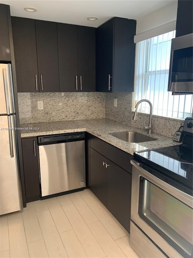 kitchen featuring tasteful backsplash, light stone counters, appliances with stainless steel finishes, and sink