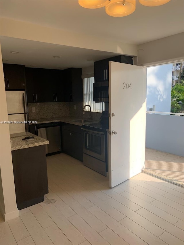 kitchen with backsplash, stainless steel appliances, sink, and light stone counters