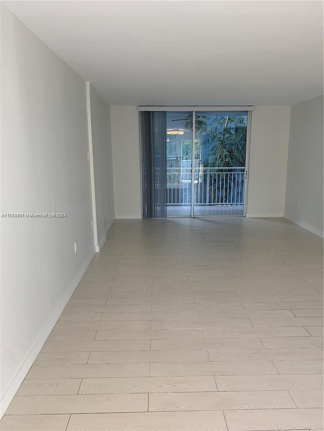 unfurnished room featuring light tile flooring and a wall of windows