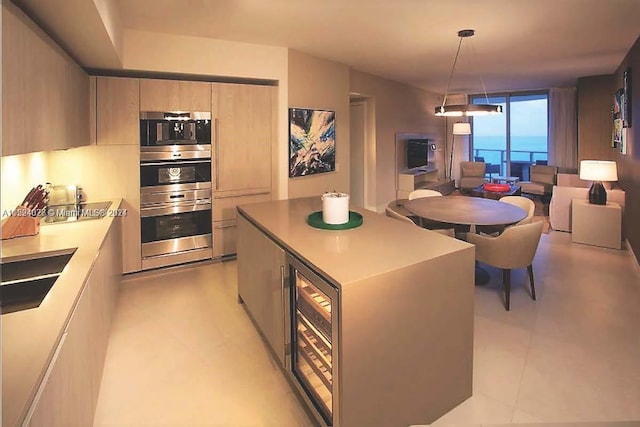 kitchen featuring pendant lighting, a center island, light brown cabinetry, a water view, and sink